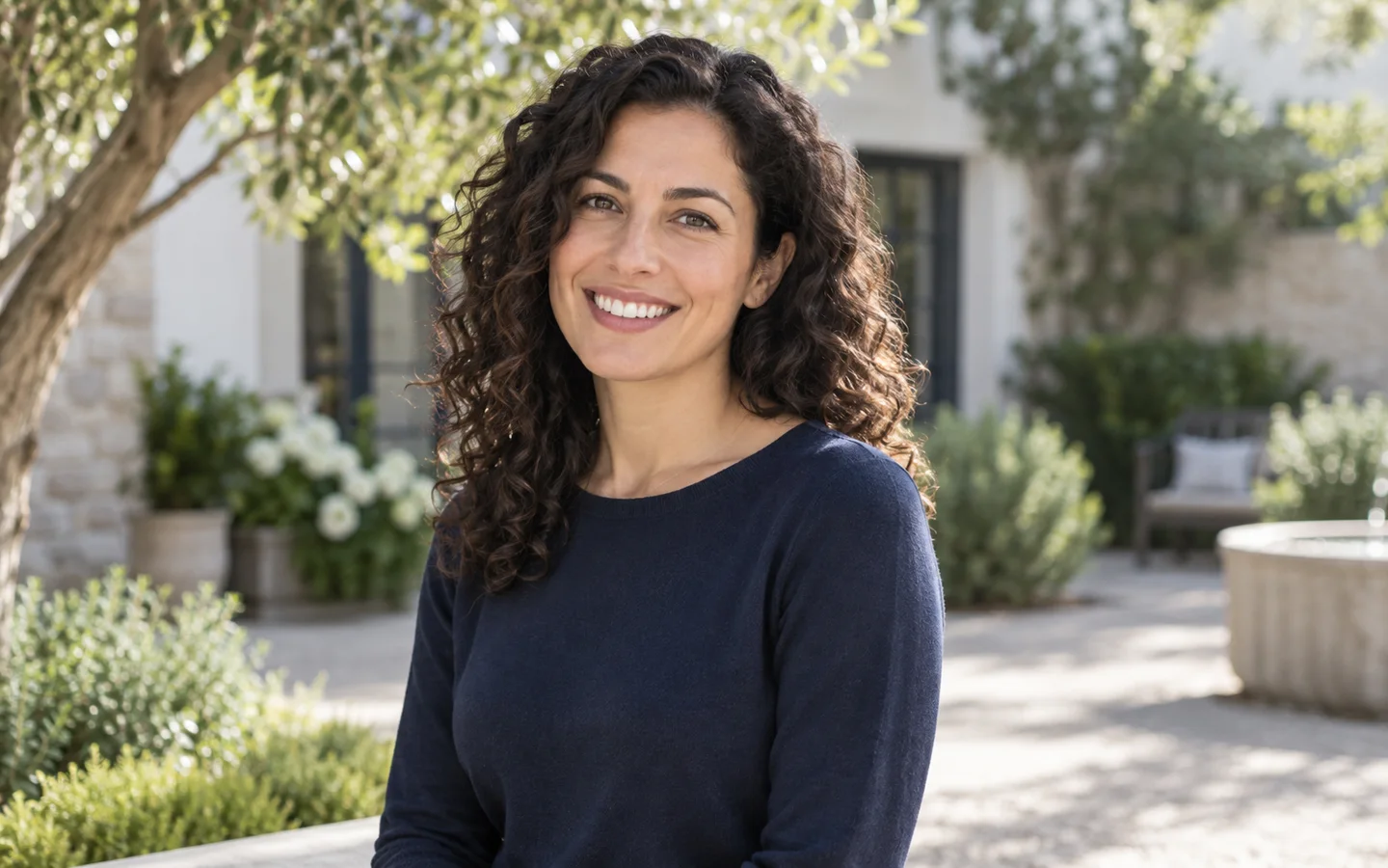 Woman smiling in a sunlit courtyard